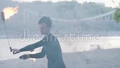 职业男子在树前的河岸上用火扇<strong>表演节目</strong>的肖像。 技能射击